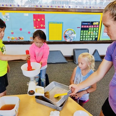 Moms are welcome in our classroom. Here Christina Niehues is helping the K-class make apple sauce!